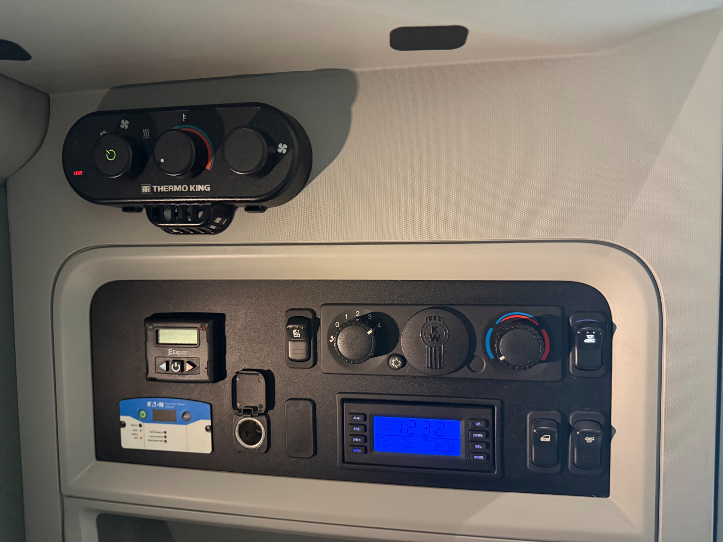 Kenworth T680 cabin dashboard showing Thermo King unit and control panel with blue-lit radio/display, switches, and climate dials.