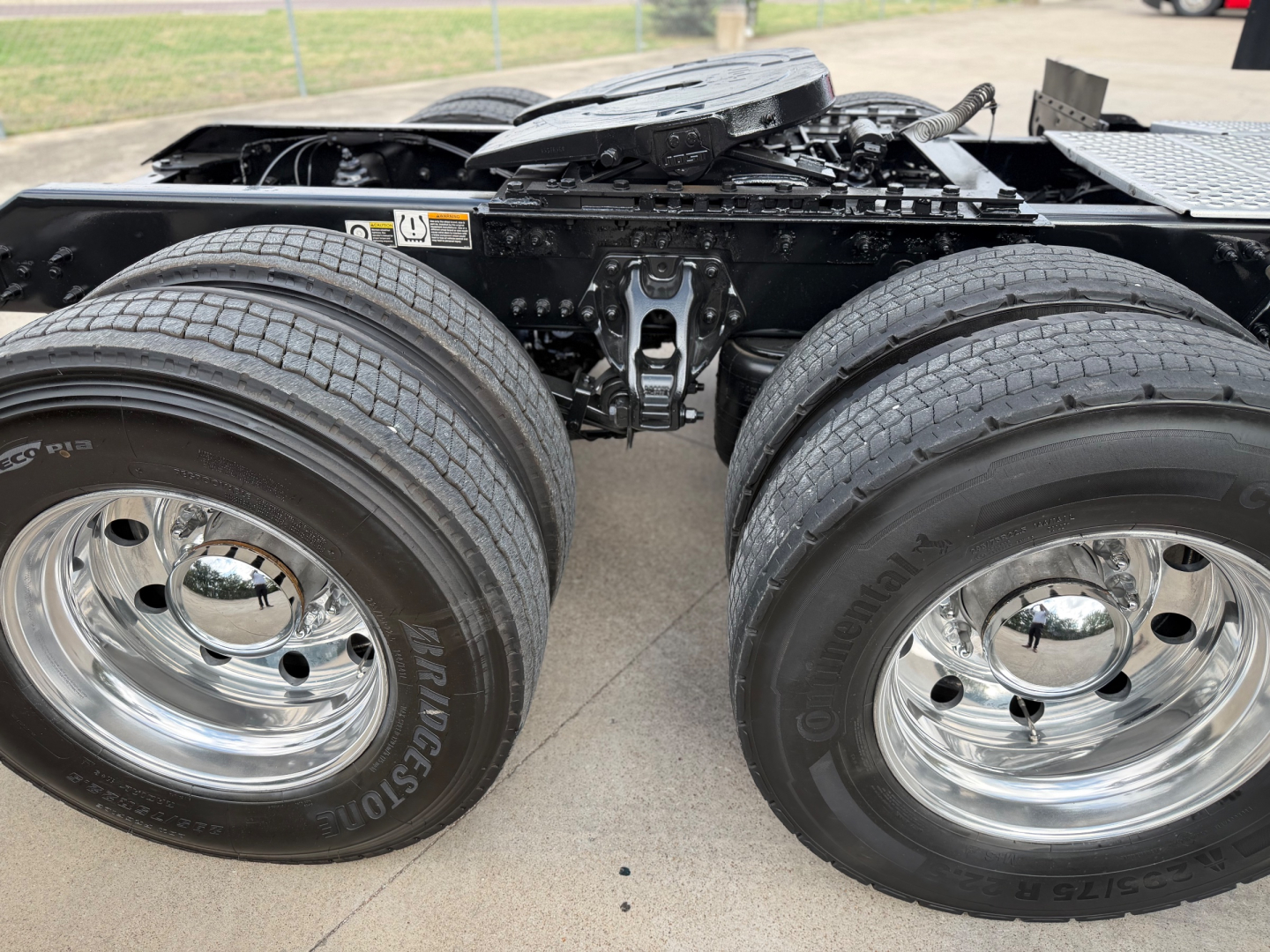 Kenworth T680 chassis with dual rear axles and chrome wheels, showing suspension and frame. No visible text on components.