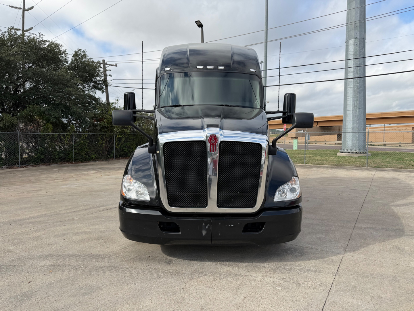 Kenworth T680 front view showing large black grille, chrome surround, dual upright mirrors, headlights, and Kenworth logo on grille.