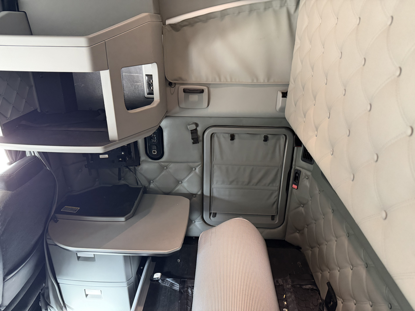 Kenworth T680 sleeper cab interior showing side door with quilted headliner and storage compartments.