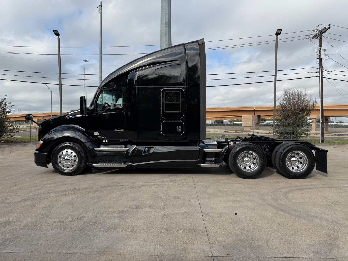 Kenworth T680 tractor side view showing aerodynamic sleeper cab and dual rear axles with chrome wheels.