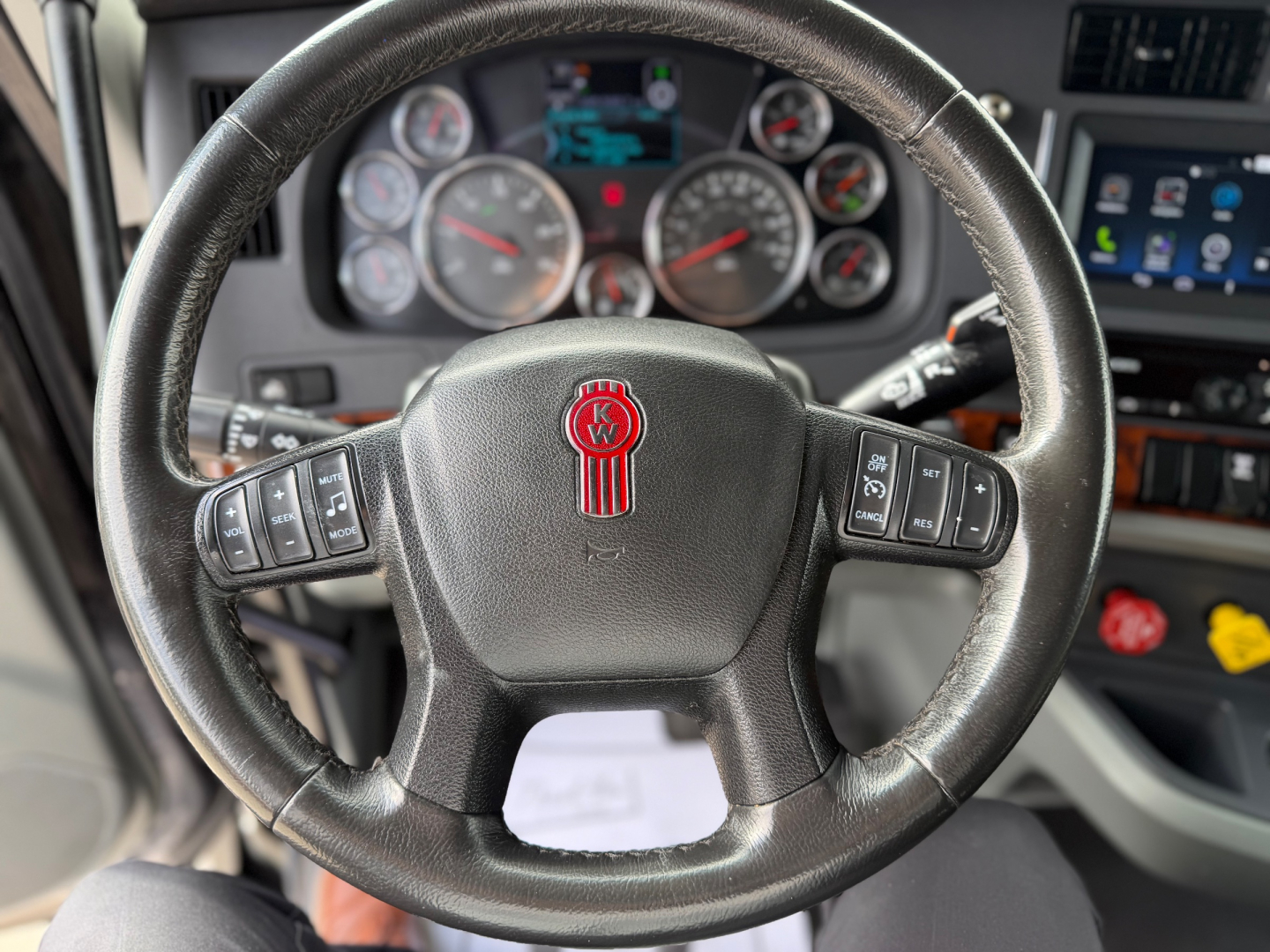 Kenworth T680 steering wheel and instrument cluster inside cab showing round gauges and center display.