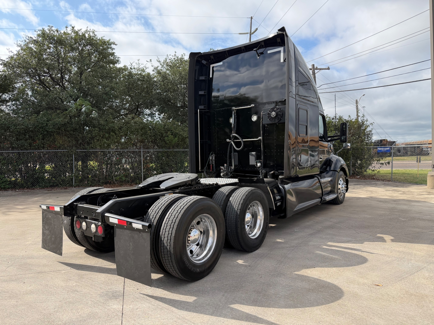 Kenworth T680 tractor rear view showing tandem axles and fifth wheel, black exterior, fuel and battery compartments visible.