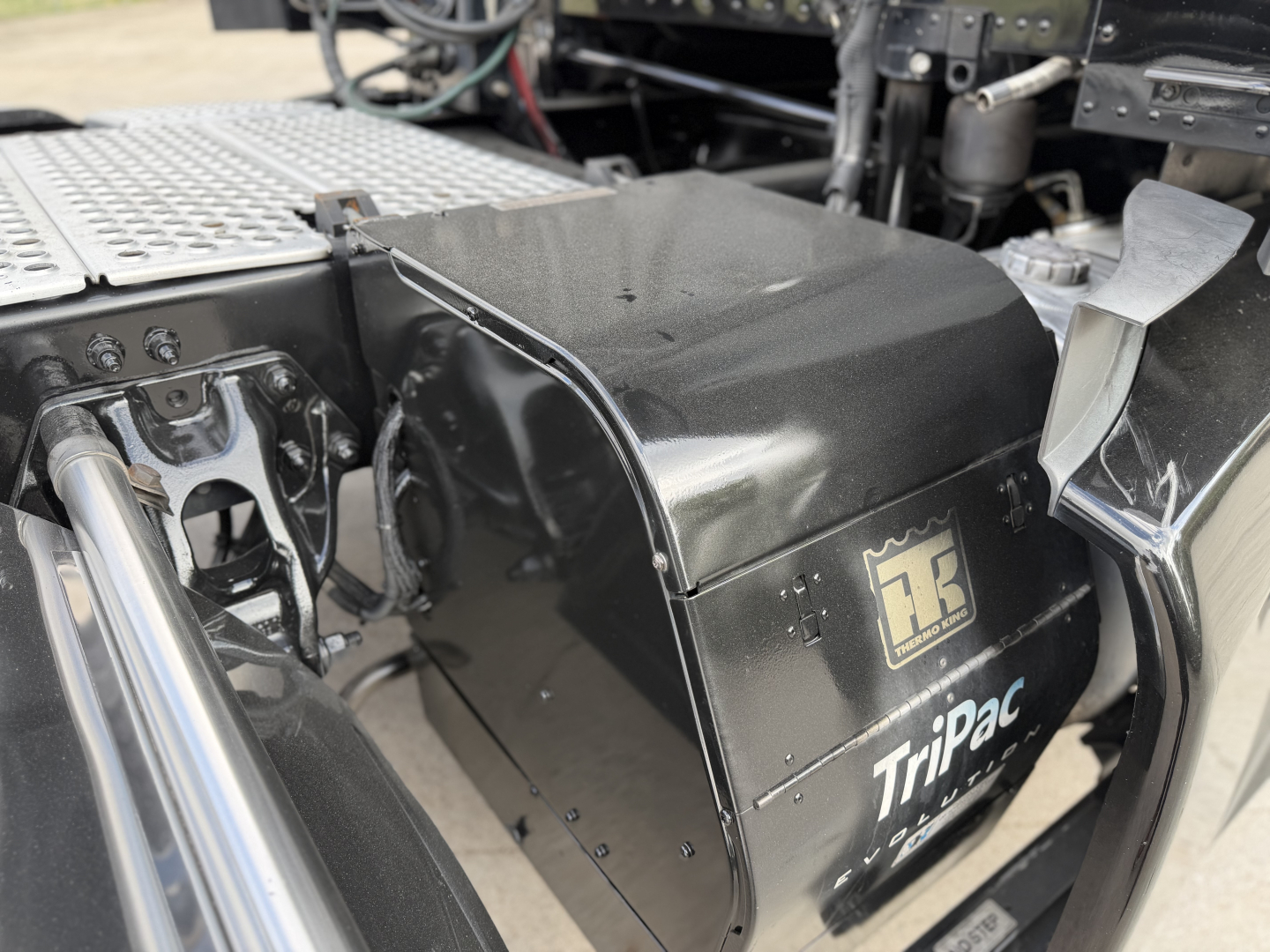 Kenworth T680 truck chassis side view showing TriPac auxiliary power unit (APU) housing with logo and panels.