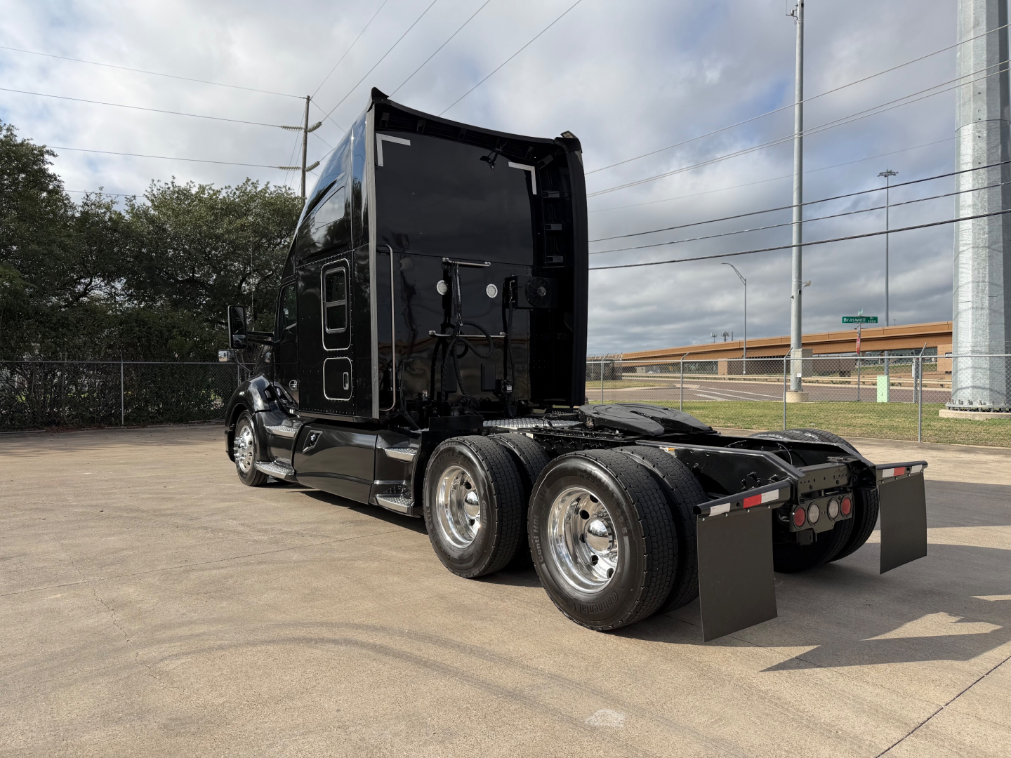 Kenworth T680 tractor with sleeper cab, rear view showing dual rear axles, hitch area, and black exterior; no visible text on components.