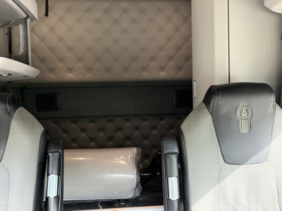 Kenworth T680 truck cab interior showing two front seats with quilted padded wall in background and a wrapped item in between seats.