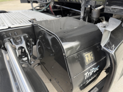 Kenworth T680 truck chassis side view showing TriPac auxiliary power unit (APU) housing with logo and panels.
