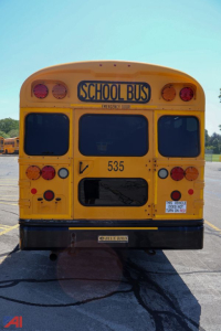 Rear view of a yellow 2018 Blue Bird Vision school bus showing emergency door, lights, and bus number 535.