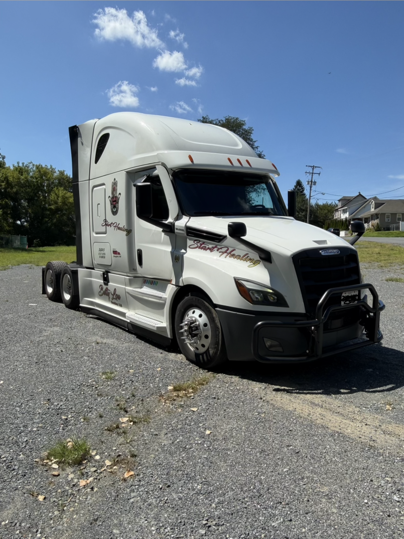 Freightliner Cascadia highway tractor showing cab details and decals; side shows '555' style script and company graphics; front grille and bumper visible.