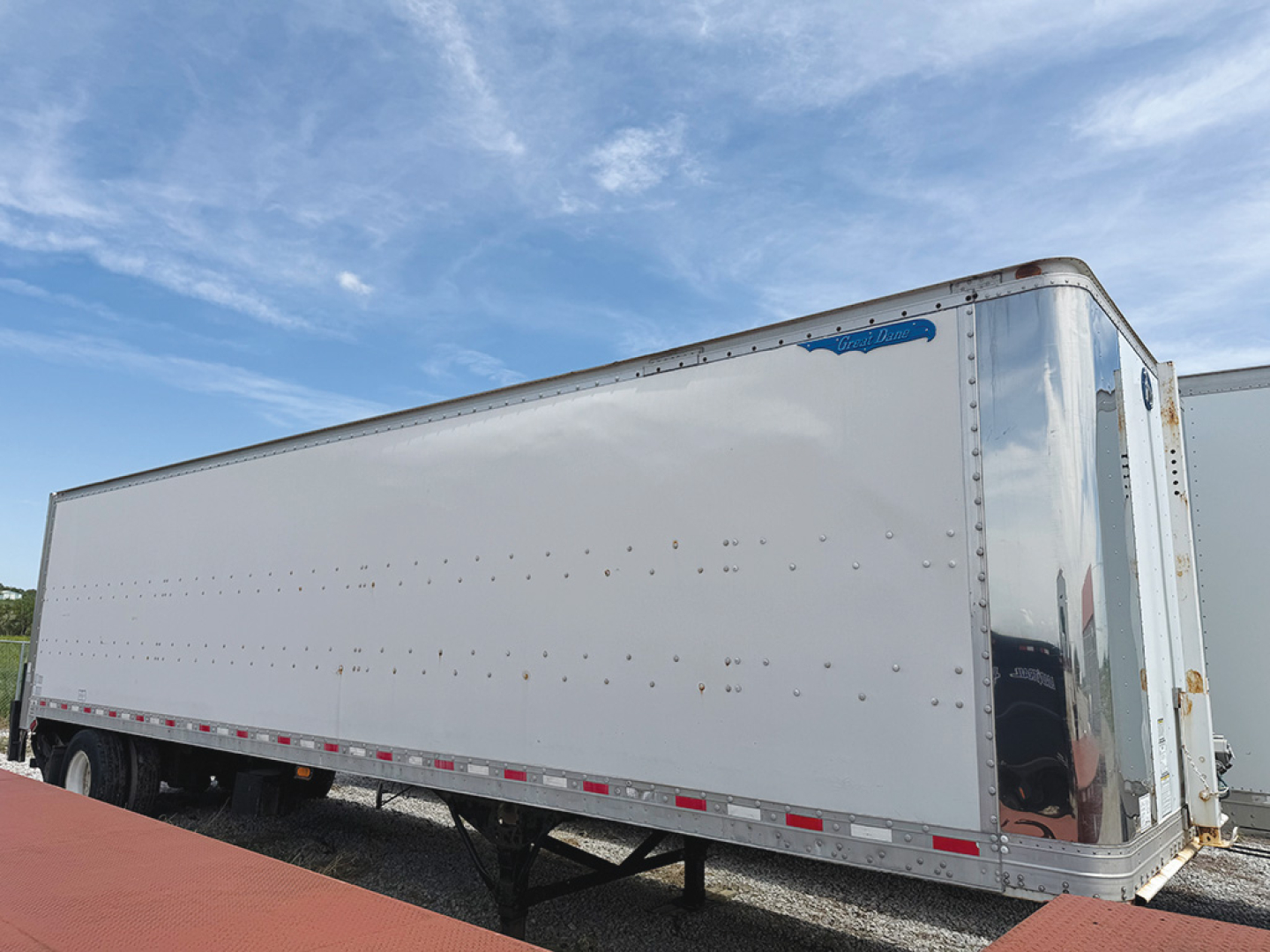 Great Dane aluminum van trailer (side view) showing riveted white extrusion, blue logo near front, rear corner protected by polished panel, dual rear doors.