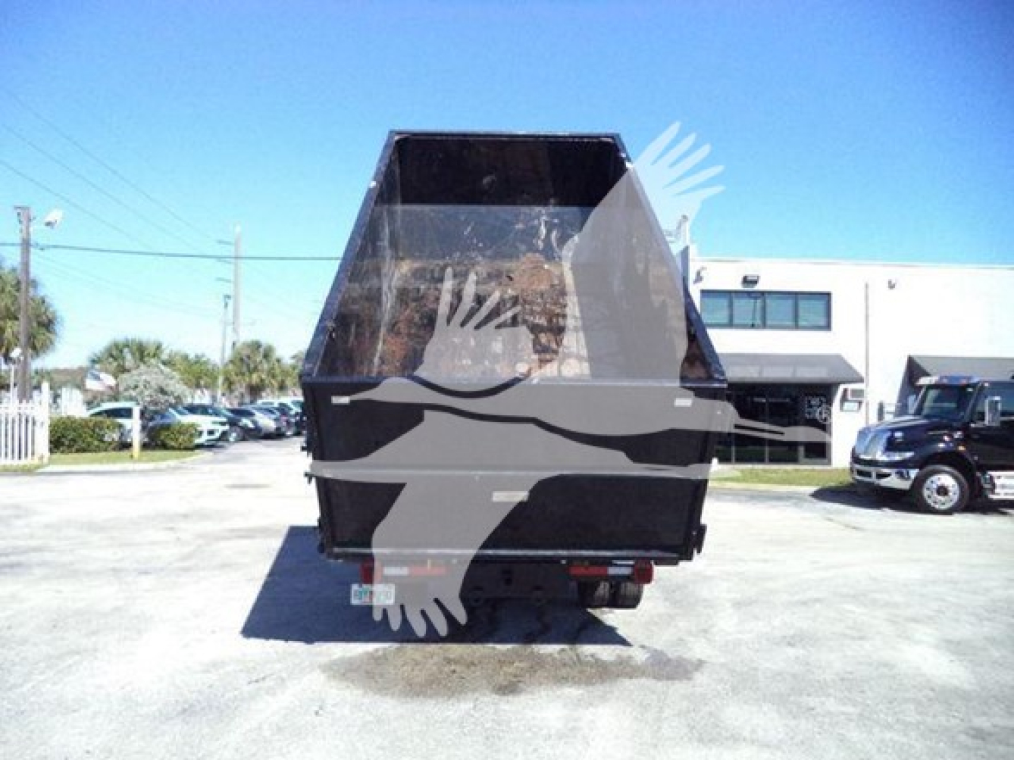 Truck rear view of a 2023 Chevrolet Silverado 6500HD rolloff with dump bed in a parking lot.