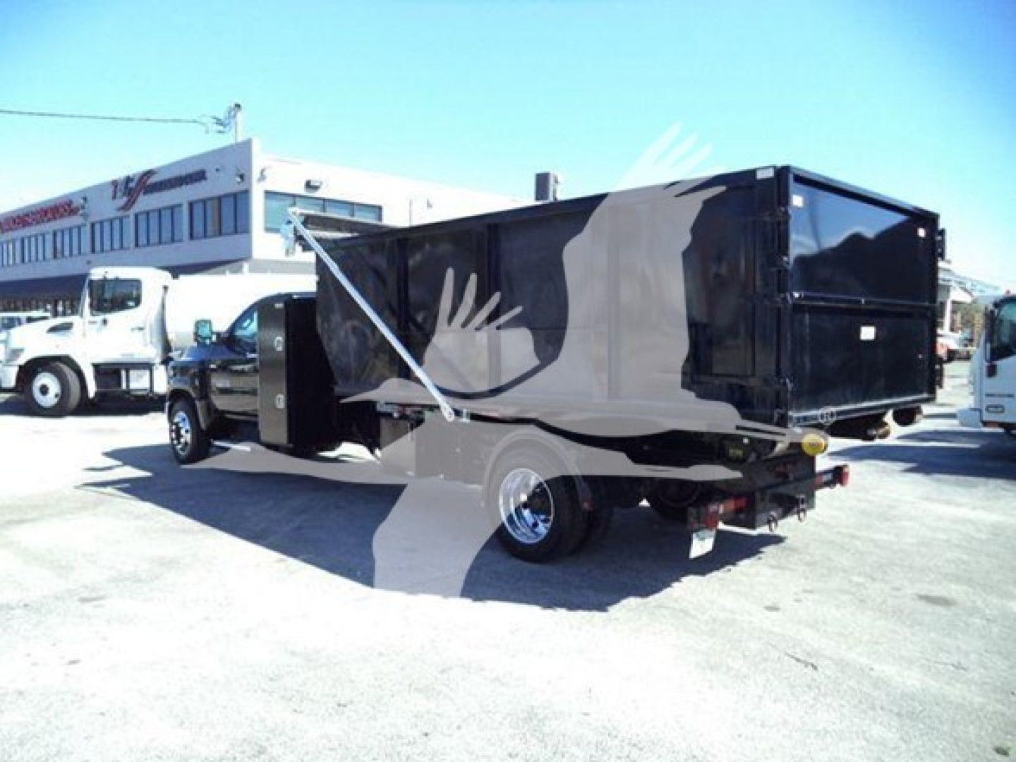 Truck bed of a 2023 Chevrolet Silverado 6500HD rolloff truck showing black dump body and rear hitch.