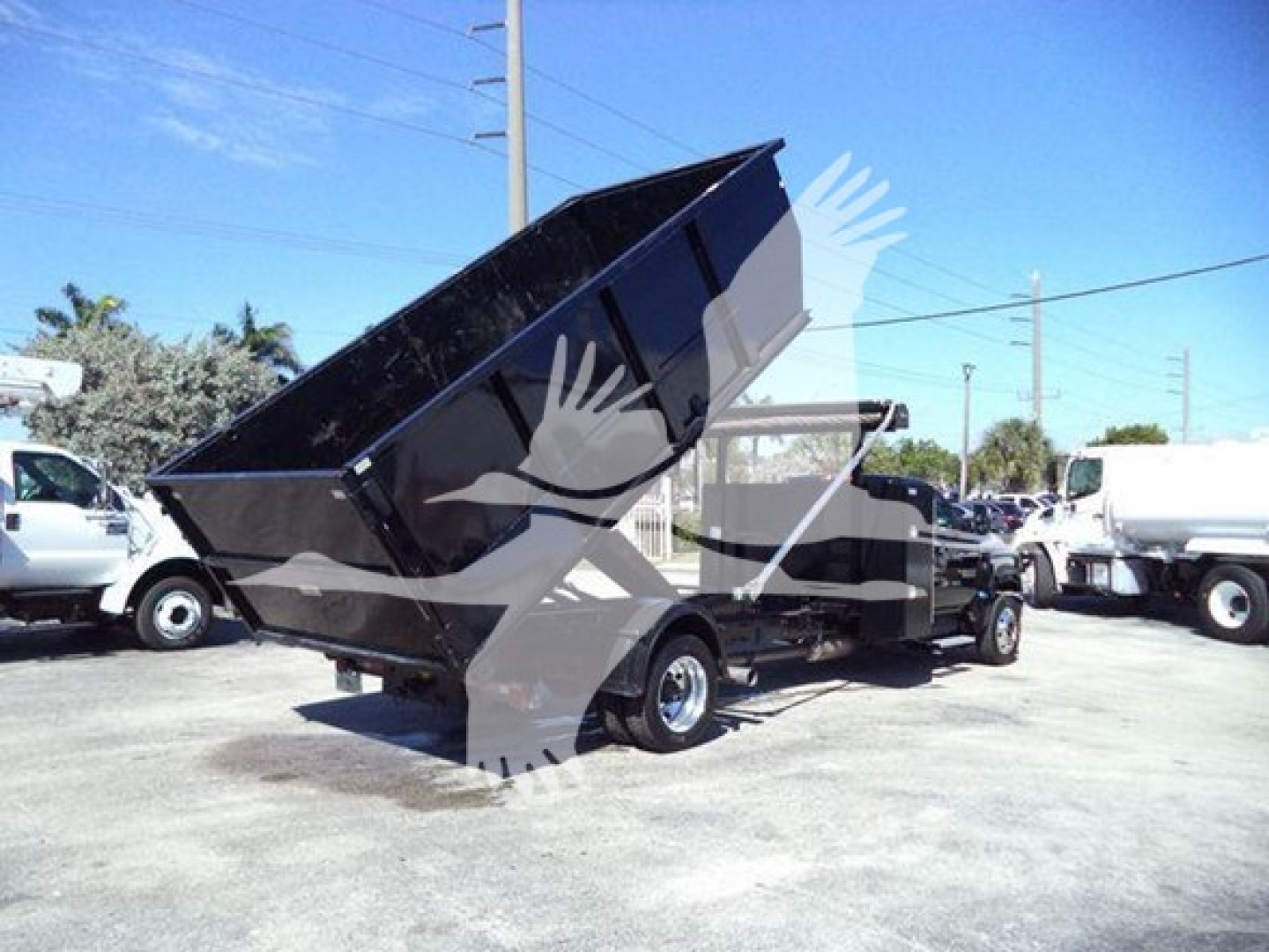 Dump truck bed in raised position on a 2023 Chevrolet Silverado 6500HD roll-off truck, side view showing hydraulic hoist and rear wheels.