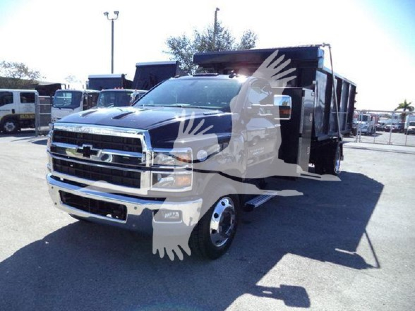 Chevrolet Silverado 6500HD roll-off truck in service bay showing front grille and bed with logo and chrome accents.
