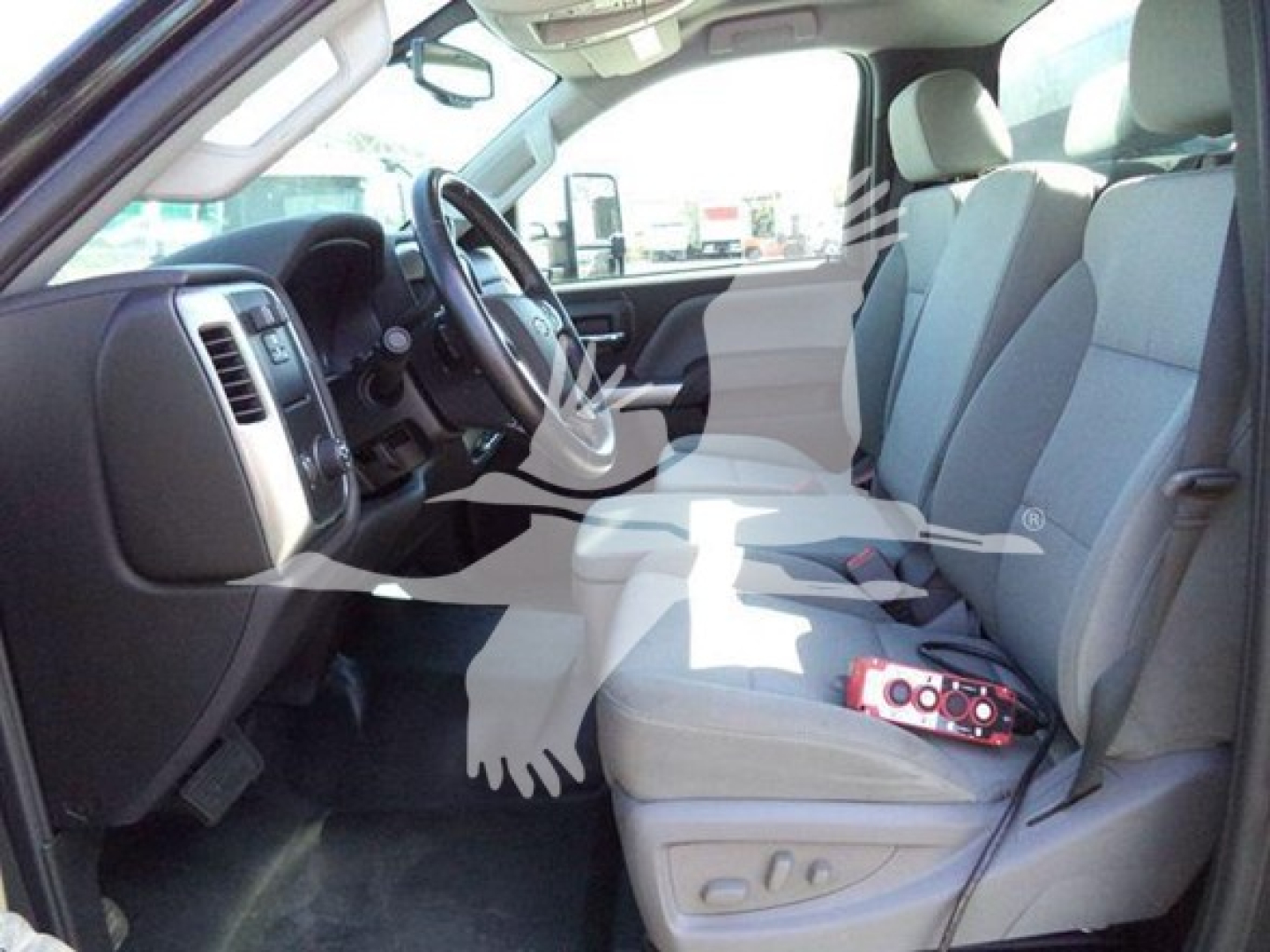 Truck interior showing front seats and dashboard of a Chevy Silverado 6500HD with light gray cloth seating.