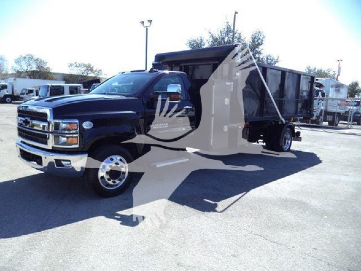 Truck in a used lot: 2023 Chevrolet Silverado 6500HD roll-off truck with black cab and long dump bed; VIN 1HTKHPVM8PH685711; stock T85711.