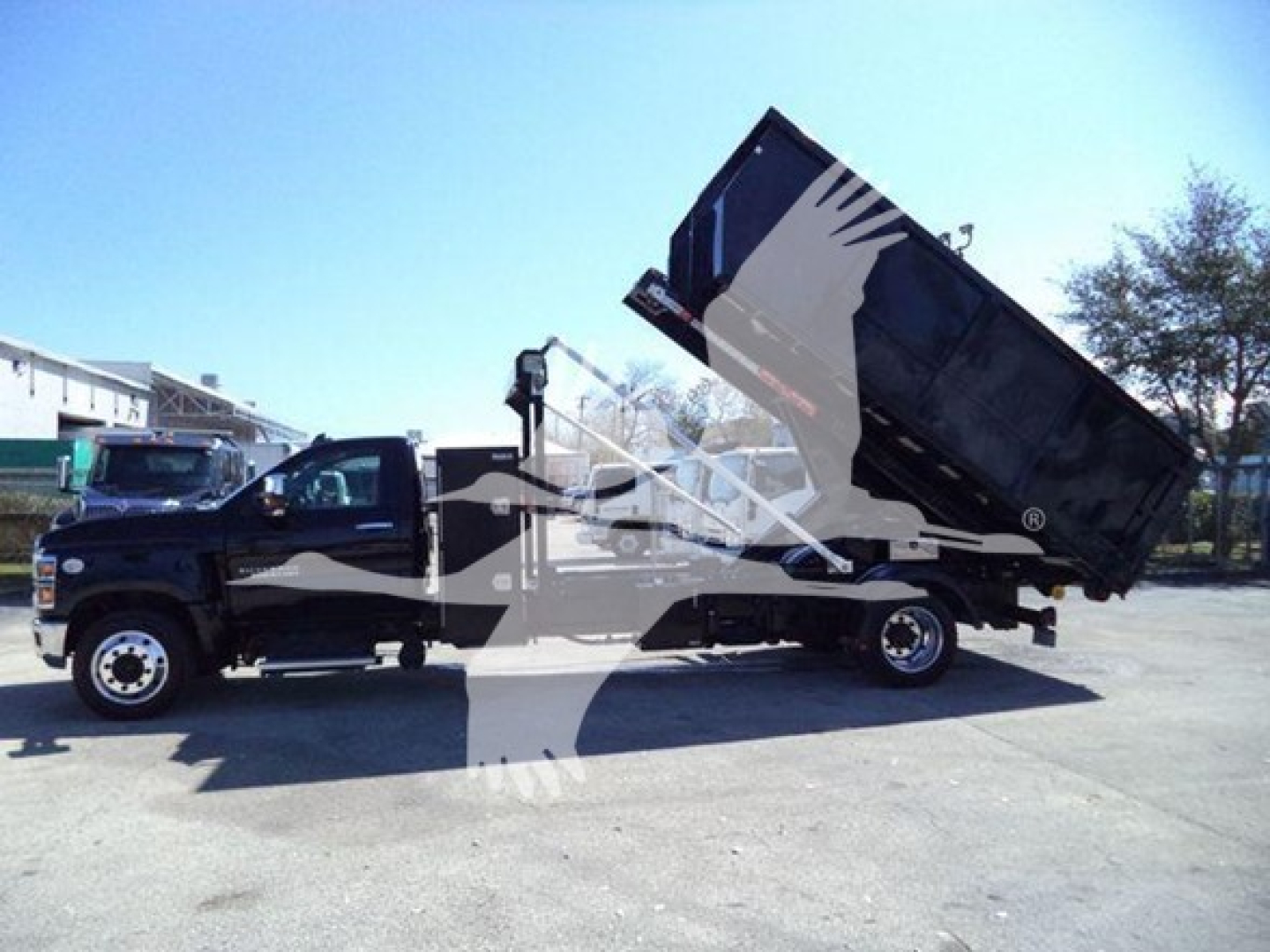 Chevrolet Silverado 6500HD roll-off truck with dump bed raised showing side profile and cab