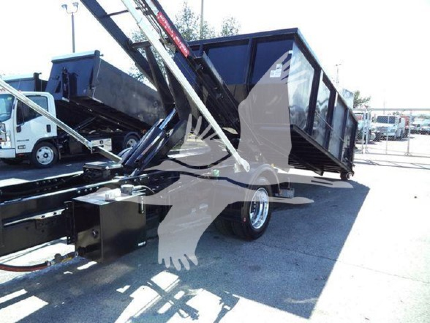 Truck bed with roll-off hoist on a Chevrolet Silverado 6500HD, side view showing hydraulic arms and container, in-service condition.