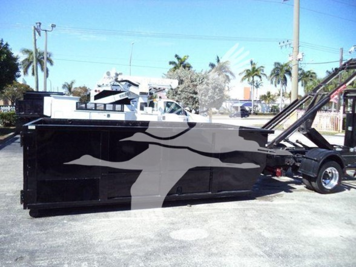 Truck: 2023 Chevrolet Silverado 6500HD roll-off body with graphic design on side, side view showing chassis and loading mechanism.