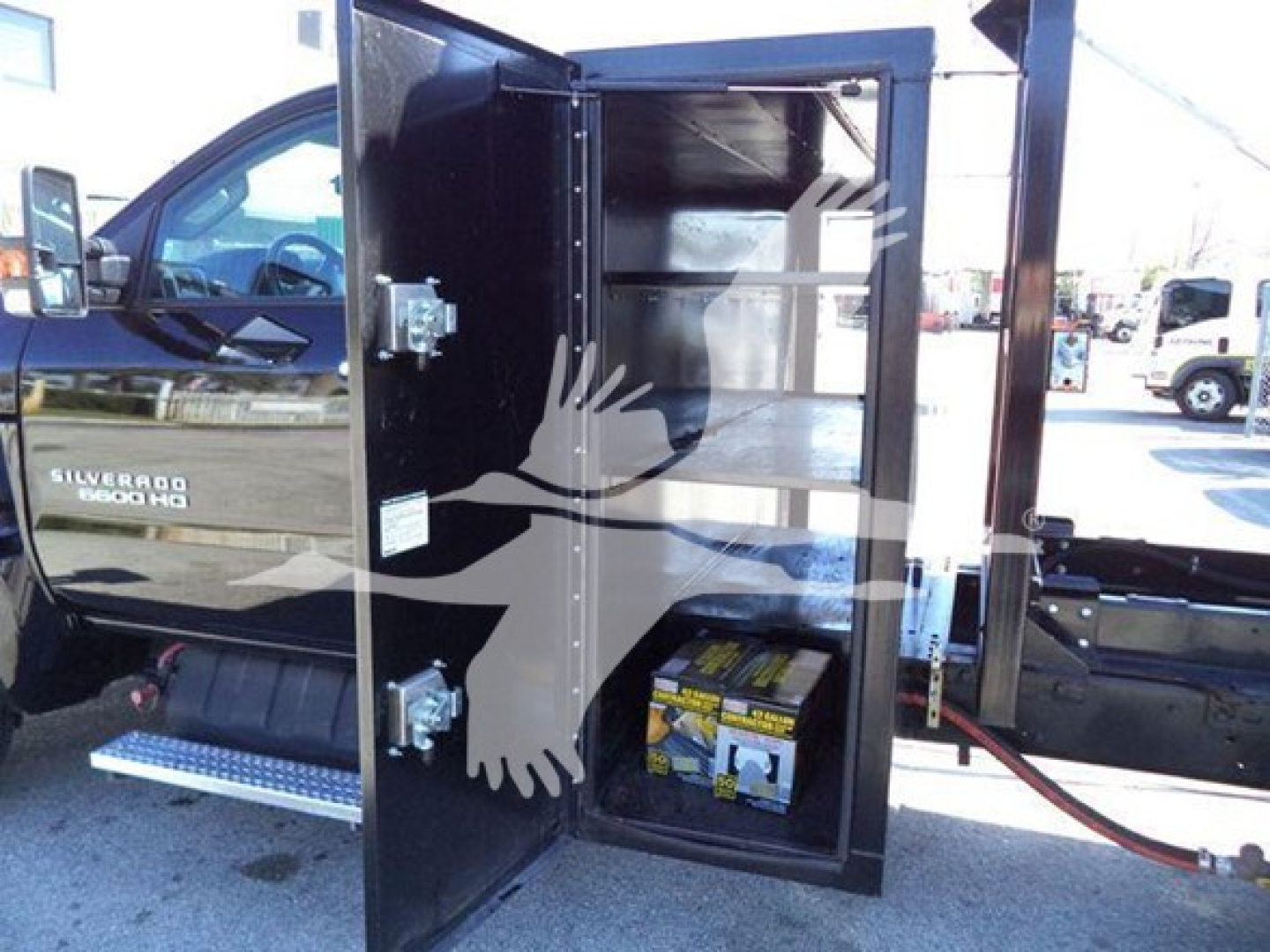 Chevrolet Silverado 6500HD roll-off truck compartment open showing battery and storage shelves