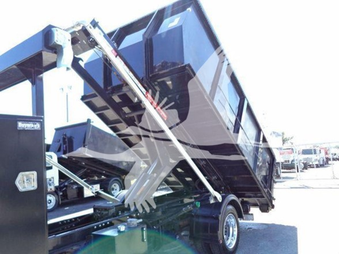 Truck rear with roll-off hoist and hydraulic arms in a Silverado 6500HD front view showing cargo bed and hydraulic mechanism.