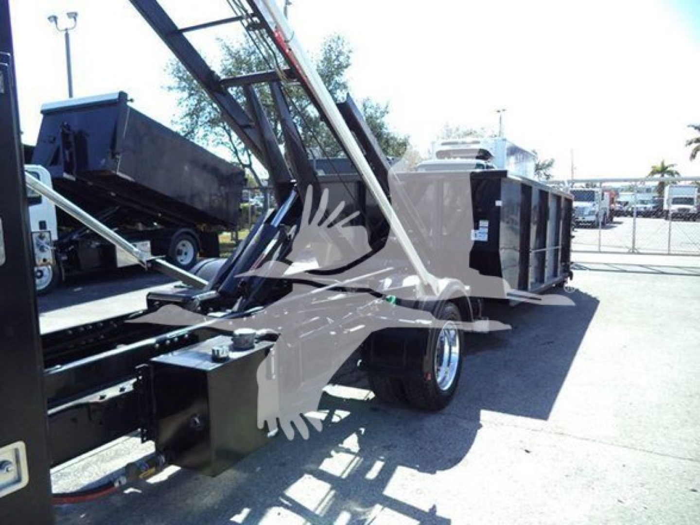 Rolloff truck chassis and hydraulic arm on a 2023 Chevrolet Silverado 6500HD; visible labels not legible; front wheel and dump bed machinery present.
