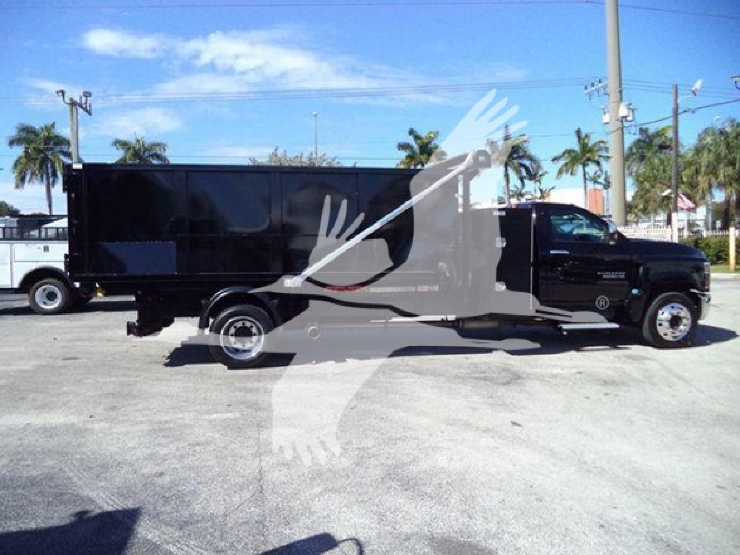 Vehicle side view of a black 2023 Chevrolet Silverado 6500HD roll-off truck with a long rectangular cargo box.