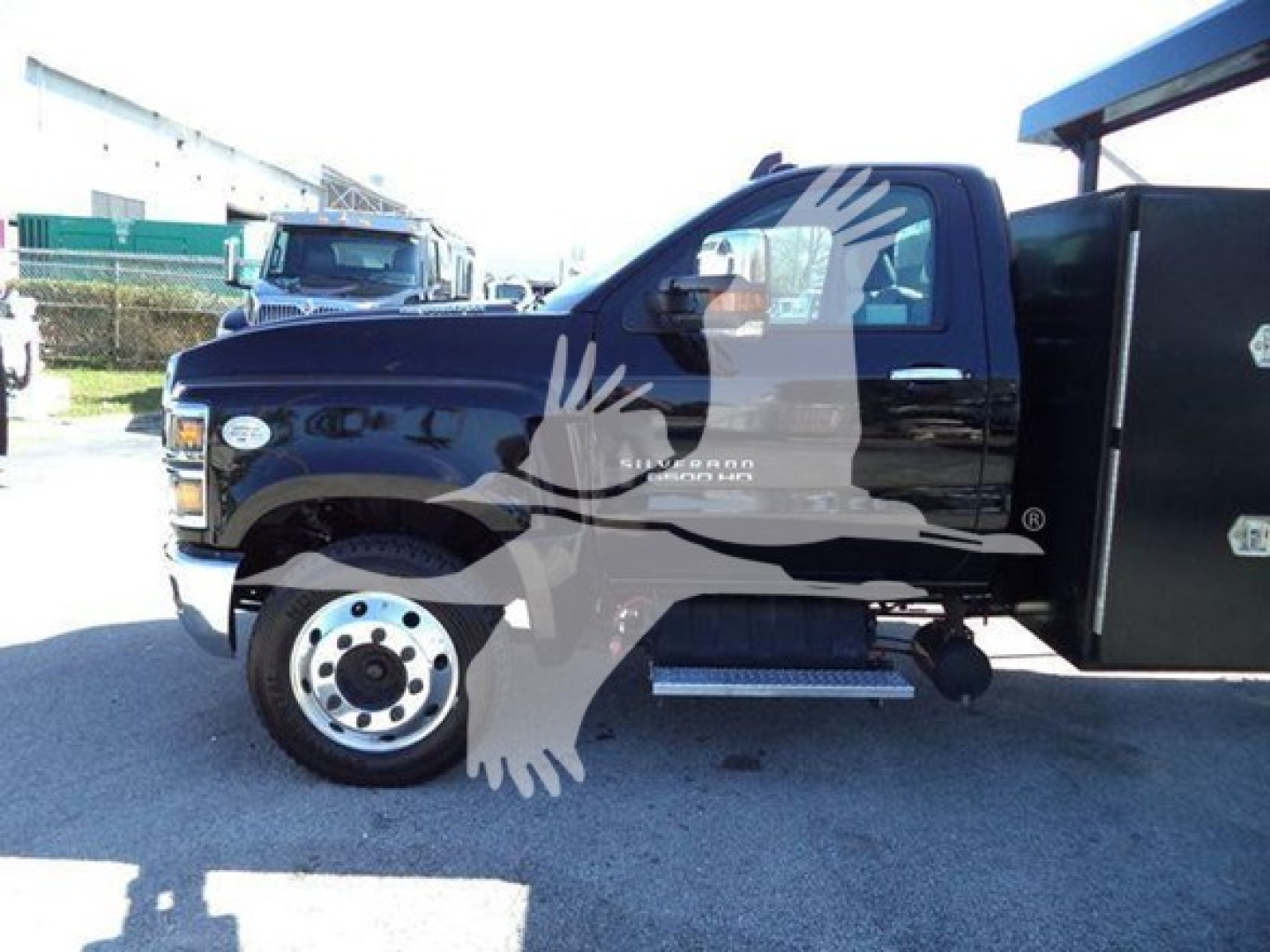 Truck side view showing Chevrolet Silverado 6500HD logo on door and black utility body. Visible text includes branding on door and step/side rail.