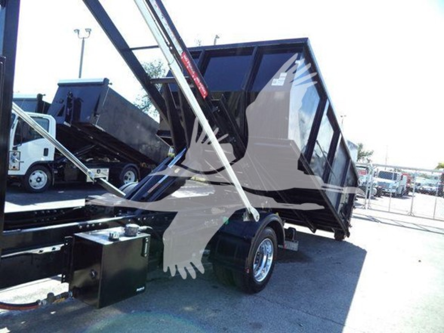 Truck bed with dump tarp in raised position, rear view of a Silverado 6500hd dump truck hauling equipment and hydraulic components visible.