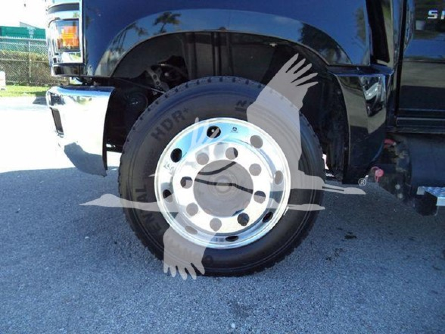 Truck wheel and front fender of a 2023 Chevrolet Silverado 6500HD, visible chrome wheel, tire, and part of the body; HDR image watermark partially over wheel.