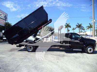 Truck photo showing a black 2023 Chevrolet Silverado 6500HD with a raised dump bed, side view, in a dealership lot.