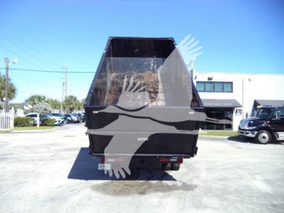 Truck rear view of a 2023 Chevrolet Silverado 6500HD rolloff with dump bed in a parking lot.