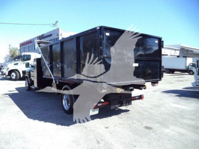 Truck bed with a black dump trailer attached, rear view showing tailgate and hitch, Silverado 6500hd in a lot