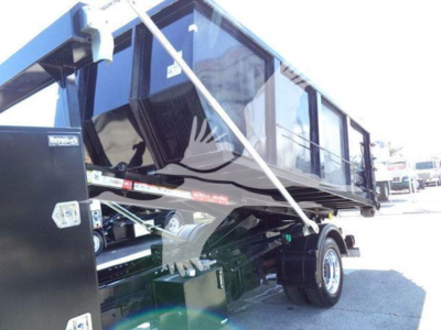 Truck bed/dump body mounted on a Chevrolet Silverado 6500HD chassis showing hydraulic latches and side rail; image includes part of cab and dual rear wheels.
