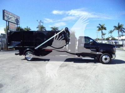 Truck side view of a 2023 Chevrolet Silverado 6500HD dump/roll-off with black dump body, chrome wheels, and extended cab, bearing stock number T85711.