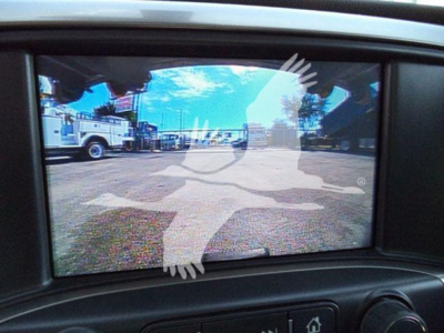 Truck camera display showing a view of a lot with service trucks and a faint overlay graphic.