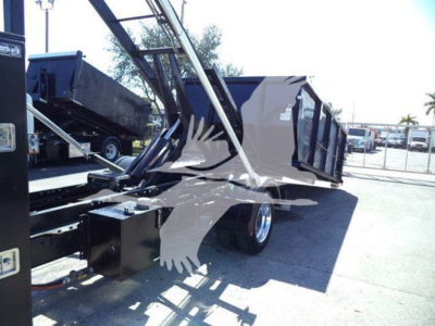 Truck bed with hydraulic ramps and flatbed on a Silverado 6500HD utility/rolloff body showing side panels and rear wheels.