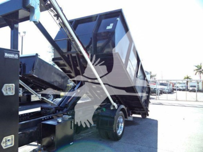 Truck image of a 2023 Chevrolet Silverado 6500HD rolloff body in raised position showing hydraulic components and bed retraction.