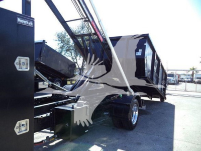 Truck bed showing hydraulic crane and rear wheel of a Chevrolet Silverado 6500HD, with loading apparatus and black cargo bed. Visible text includes 'Buyer' on control panel.
