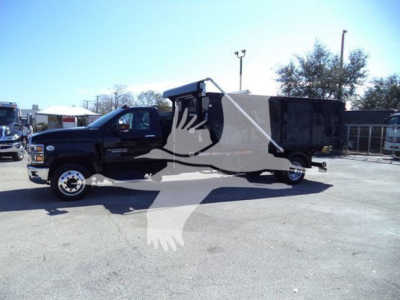 Truck cab and a roll-off dumpster body attached, black Chevrolet Silverado 6500HD in a dealership lot.