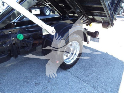 Truck wheel and undercarriage of a 2023 Chevrolet Silverado 6500HD rolloff body showing rear suspension and wheel well, green reservoir cap visible.