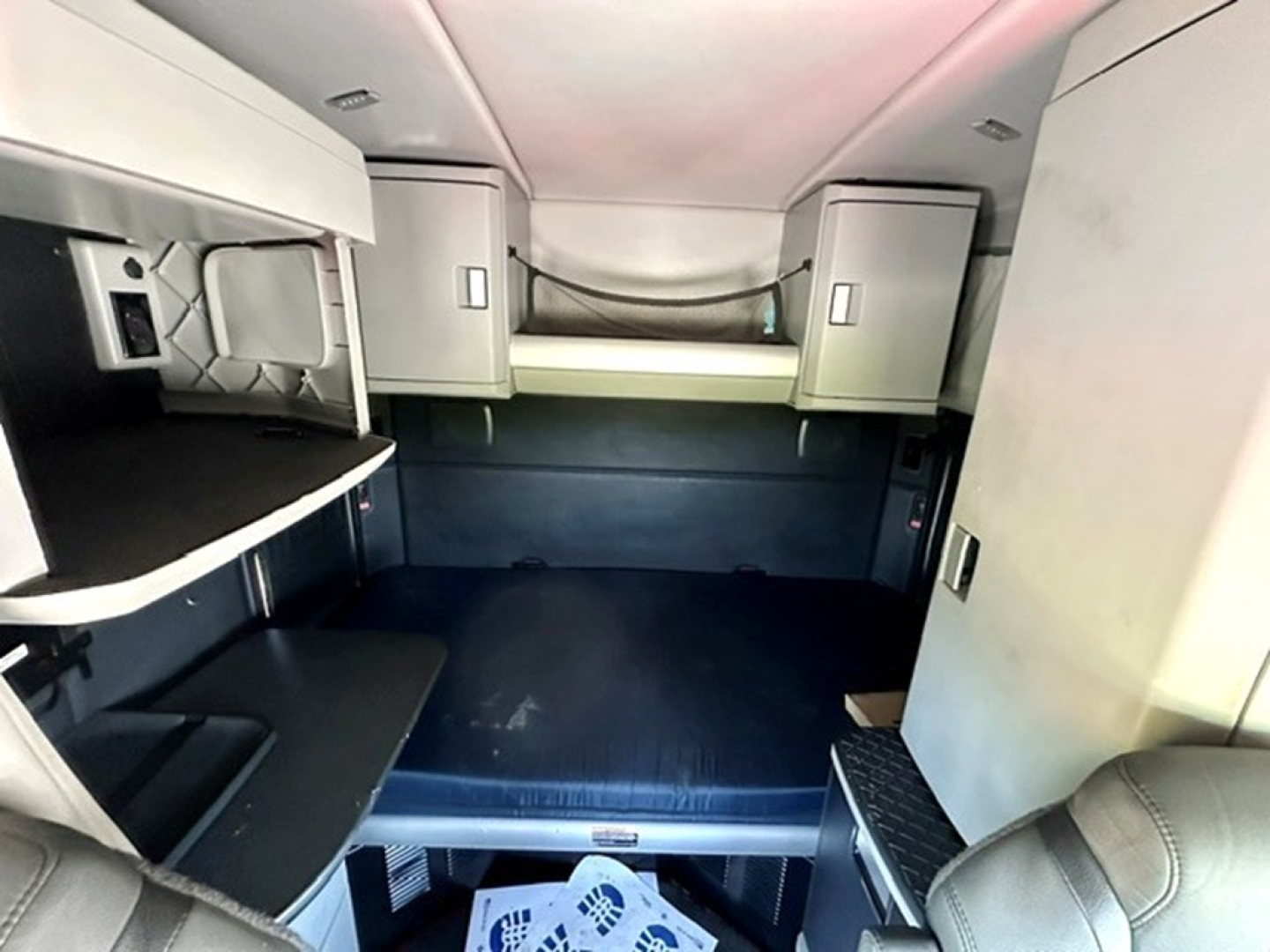 Kenworth T680 sleeper cab interior showing bunk area and storage cabinets.