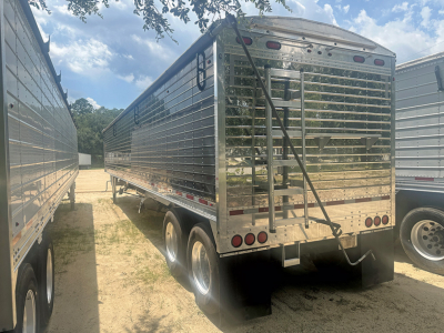 Rear view of a 2019 Wilson Pacesetter hopper trailer showing tandem wheels, chrome metal sides, rear ramp, and taillights.