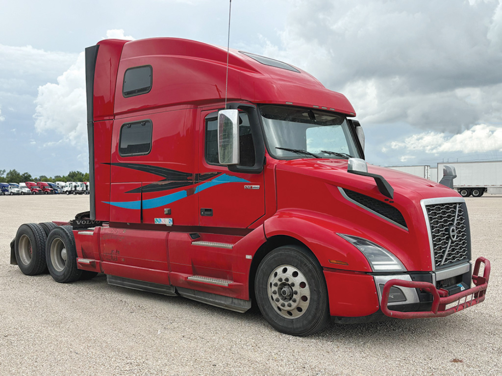 Volvo VNL 860 tractor-trailer cab in red, side view showing sleeper, aerodynamic mirrors, and chrome bumper.