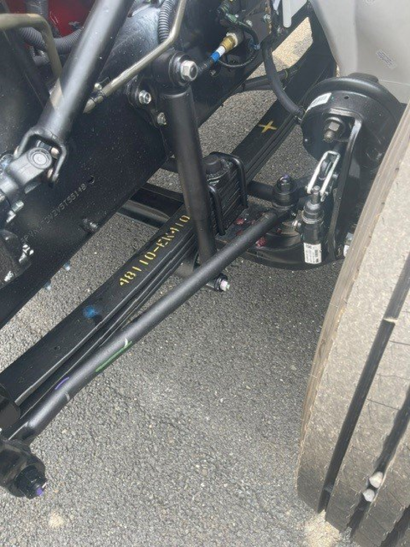 Front suspension and tie rod area of a cab chassis truck showing hydraulic lines, frame, and steering components near a wheel. Visible text on frame: 4K0-?? and various metal fittings.
