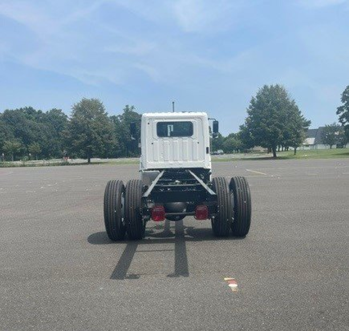 Cab chassis truck rear view showing dual rear axles and Hino L6 chassis with empty cab, white cabin, in a parking lot.