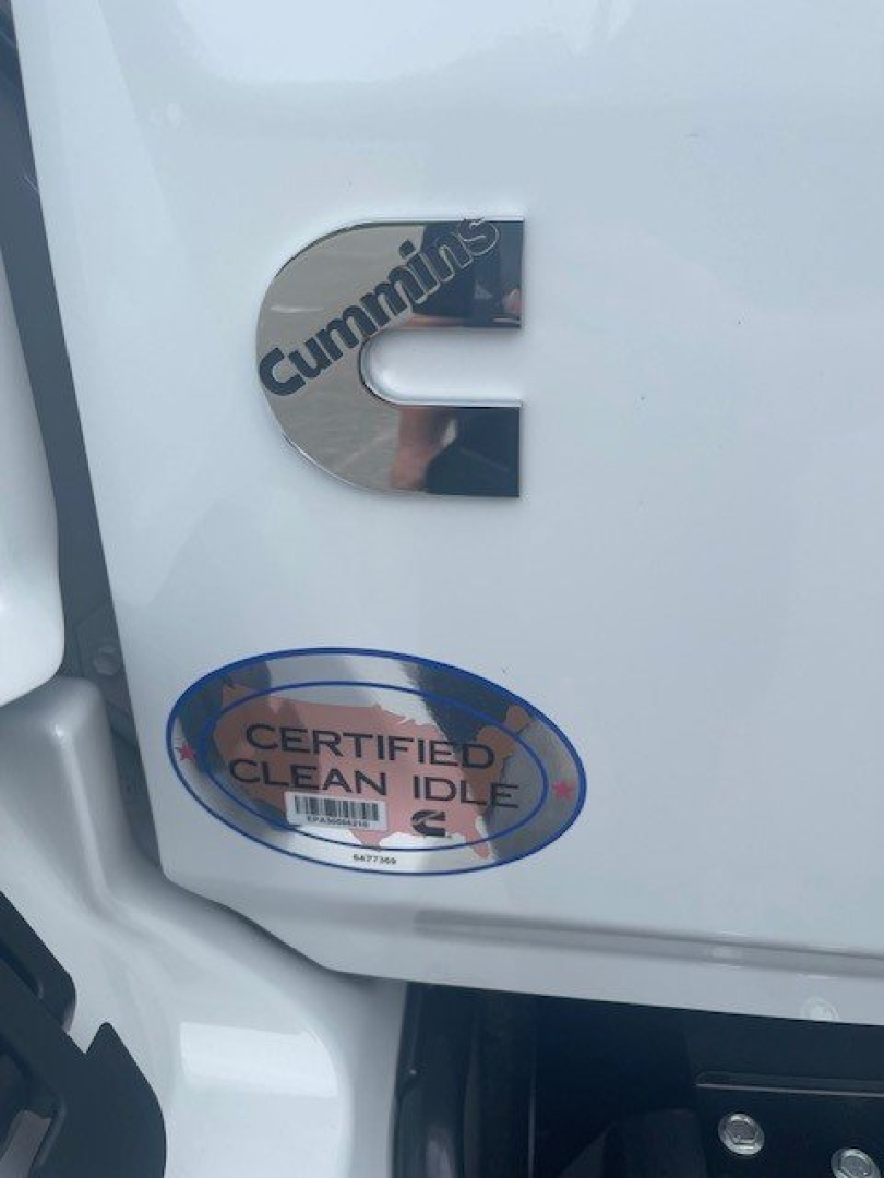 Cab chassis door with Cummins emblem and Certified Clean Idle sticker on white exterior, partial view of lower fender; 2027 Hino L6 listing context shown.