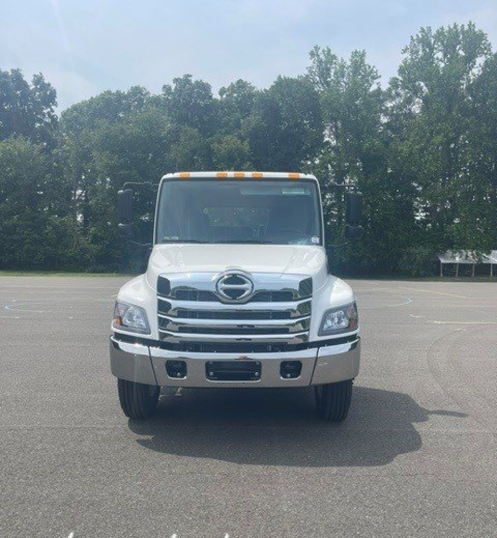 Front view of a white Hino cab chassis truck with large chrome grille, round headlights, bumper, and amber clearance lights on roof.