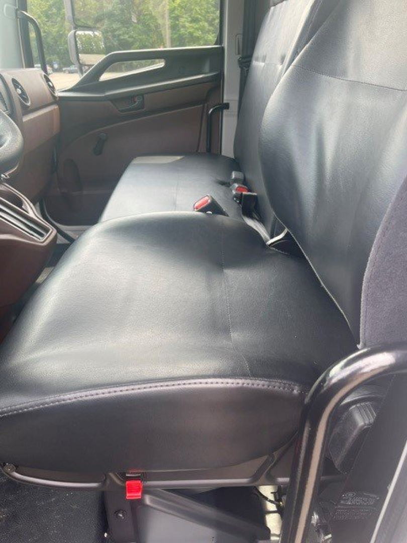 Truck interior showing front passenger and bench seat with seat belts, black leather-like upholstery, window and door panel visible.