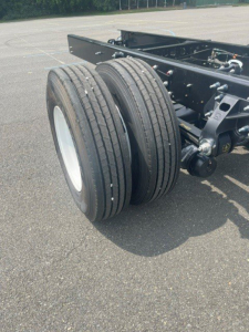 Dual rear tires of a cab chassis truck showing suspension and chassis frame with components.